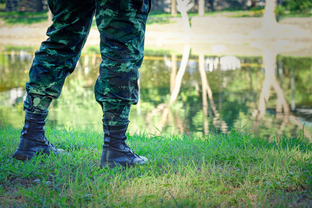 Legs of soldier standing near river, close up view, Black boots  - Photo, Image