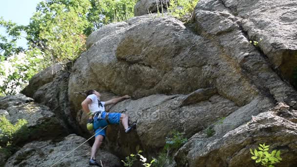 έναν νεότερό του άνδρα που σκαρφαλώνει στο βράχο, βράχο αναρρίχησης εξοπλισμού, ελεύθερη αναρρίχηση - Πλάνα, βίντεο