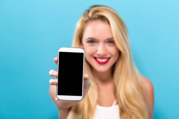 Young woman holding out a cellphone - Foto, Bild