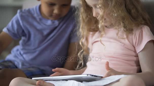 Couple of little multiethnic children playing in educational app on tablet - Video, Çekim