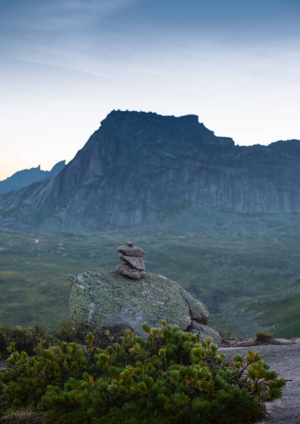 Висячий камень лежит на наклонной поверхности горы над пропастью. Огромный валун гранита и сиенита поддерживается небольшим участком на горе. Парк Эргаки. Россия
 - Фото, изображение