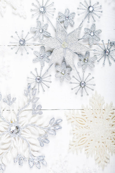 Zilverkleurige sneeuwvlokken op een witte houten achtergrond.  - Foto, afbeelding