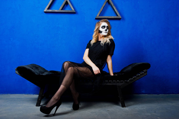 Halloween skull make up girl wear in black against blue wall at  - Foto, afbeelding