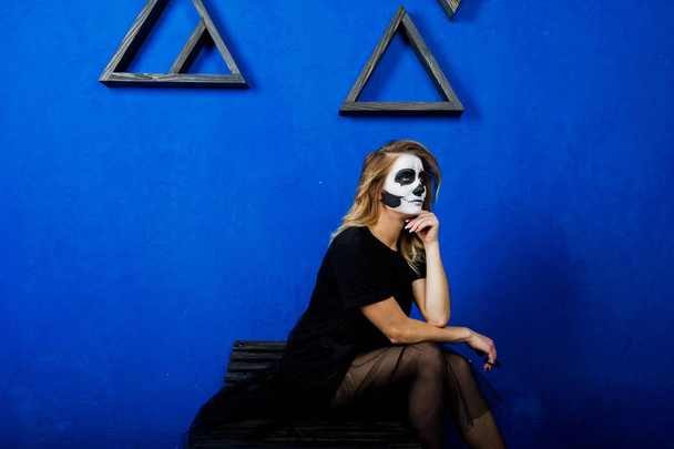 Cadılar Bayramı kafatası makyaj kız giyim siyah mavi duvara karşı  - Fotoğraf, Görsel