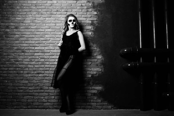 Halloween skull make up girl wear in black against brick wall at - Fotó, kép