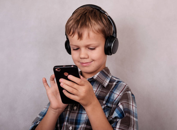 ヨーロッパの少年のヘッドフォンであなたのスマート フォンで音楽を聞く - 写真・画像