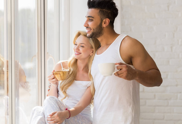 Young Beautiful Couple Stand Near Big Window, Drink Morning Coffee Cup, Happy Smile Hispanic Man Woman - Fotografie, Obrázek