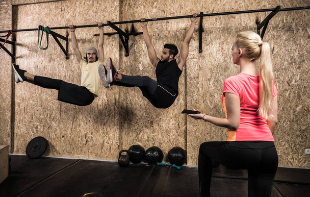 Sport Fitness ihmiset Group tekee Pull Ups vaakasuorassa baarissa Crossfit koulutus, nuori terve nainen kouluttaja
 - Valokuva, kuva