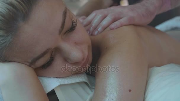 Portrét mladé ženy leží na gauči příjem masáž zad na luxusní spa salon - Záběry, video