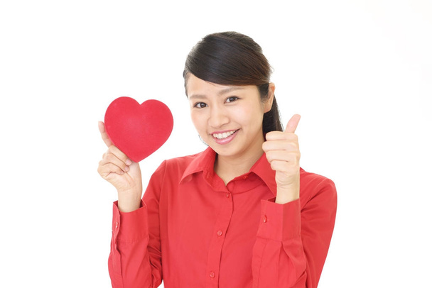Mujer sonriente con un corazón rojo
 - Foto, Imagen