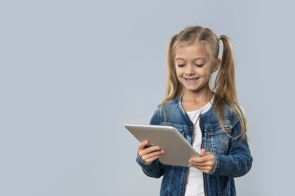 Beautiful Little Girl Using Tablet Computer Happy Smiling Wear Jeans Coat Isolated - Fotografie, Obrázek