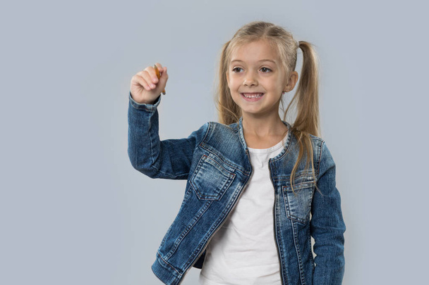 Beautiful Little Girl Hold Pencil Writing Happy Smiling Wear Jeans Coat Isolated - Valokuva, kuva