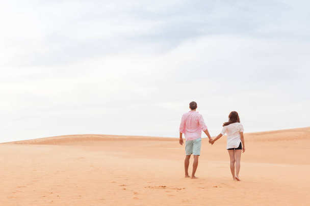 Young Man Woman Walking In Desert Couple Girl And Man Hold Hands Back Rear View Sand Dune Landscape - Фото, зображення
