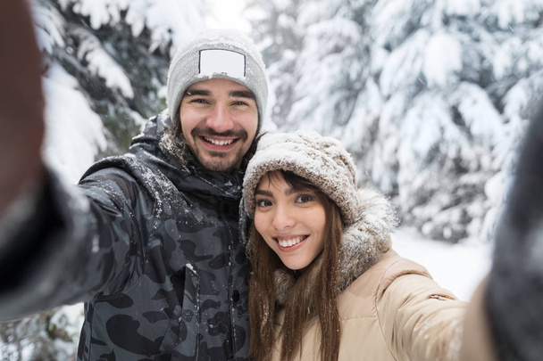 Man Taking Selfie Photo Young Romantic Couple Smile Snow Forest Outdoor - Foto, Imagen