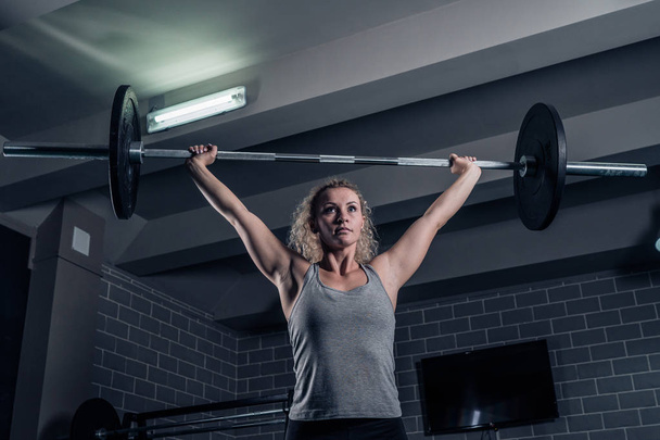Training crossfit in the gym. The girl is lifting the weight - Fotoğraf, Görsel