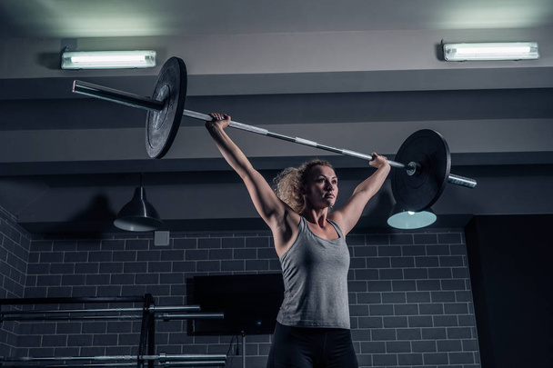 Sport muscular girl raises Barbell on CrossFit in the gym - Photo, image
