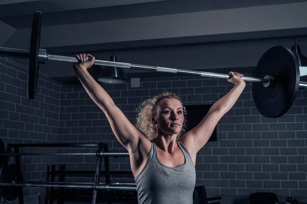 Sport muscular girl raises Barbell on CrossFit in the gym - Foto, imagen