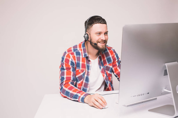 Mies työskentelee tietokoneella kuulokkeet toimistossa pöydällä
 - Valokuva, kuva