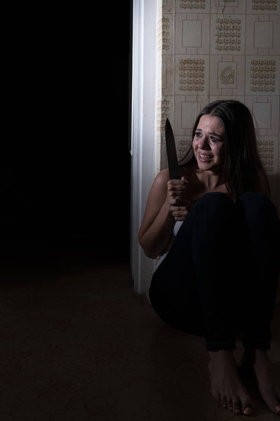 La ragazza che piange cerca di nascondersi in cucina con un coltello dal criminale
 - Foto, immagini