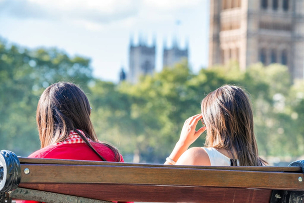 Two female tourists on a bench in front of Westminster Palace, L - Foto, Bild