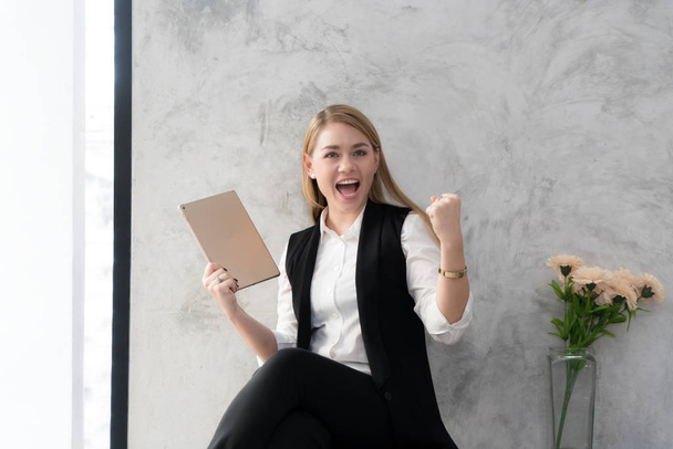 Happy businesswoman with raised in yes gesture hand reading tabl - Photo, Image