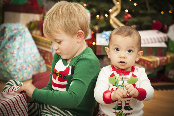Vauva ja nuori poika nauttivat jouluaamusta lähellä puuta
 - Valokuva, kuva