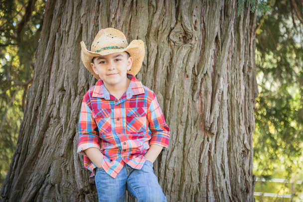 Jonge jongen gemengd ras met Cowboy hoed permanent buitenshuis. - Foto, afbeelding
