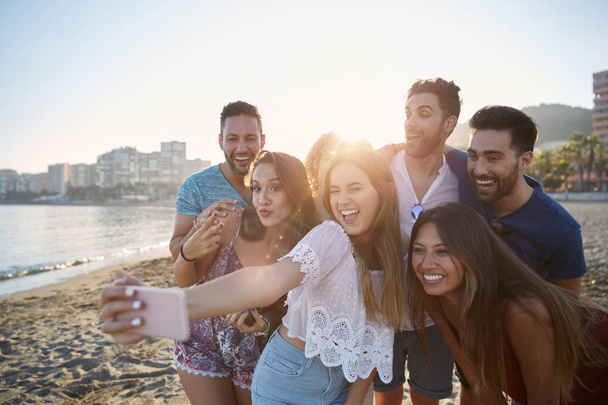 Happy girl taking selfie with friends on beach - Photo, image