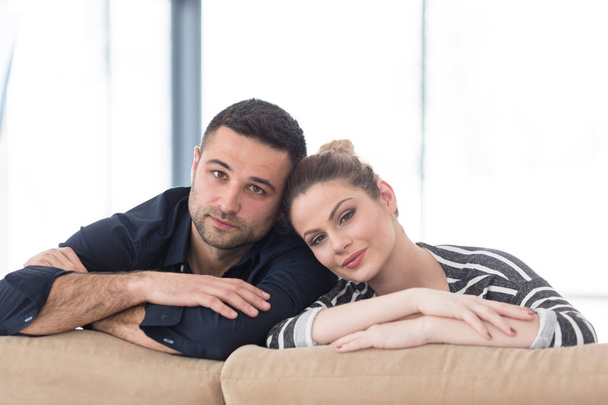 Portrait of young couple sitting on sofa - Zdjęcie, obraz