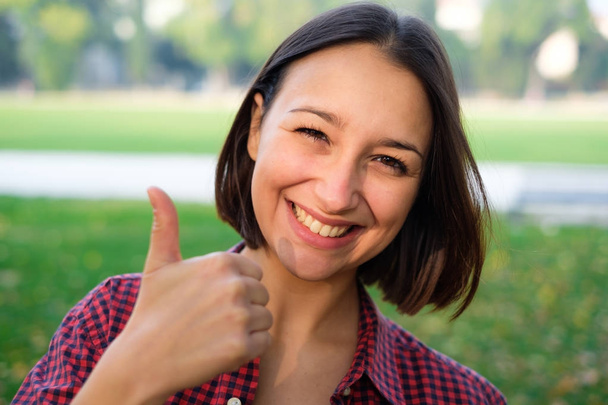 Junge fröhliche Frau fühlt sich mit Daumen-hoch-Geste positiv - Foto, Bild