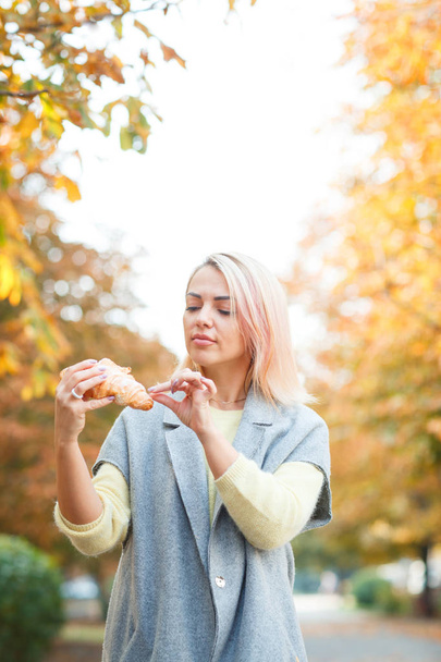 A girl is holding a croissant in her hand - Photo, image