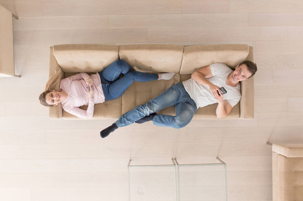 Young couple on the sofa watching television top view - Foto, imagen