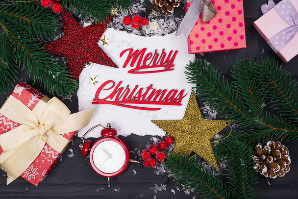 Rahmen aus Weihnachtsbaumzweigen, Geschenkschachteln, roten Uhren und Weihnachtsspielzeug um ein weißes Blatt Papier - Foto, Bild
