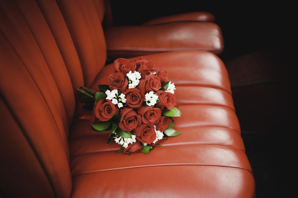 Red roses bouquet over red leather coach - Photo, image