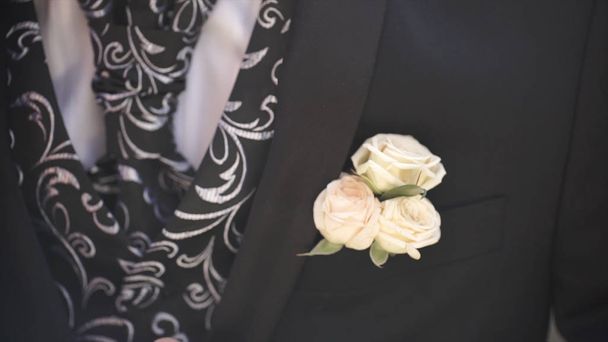 Nelkenblüte in der Tasche. die Blume in der Jackentasche. Anstecknadel mit dekorativen weißen Blumen, die an die Jacke des Bräutigams geheftet sind. boutonniere Blume in der Tasche des Bräutigams bei der Trauung - Foto, Bild