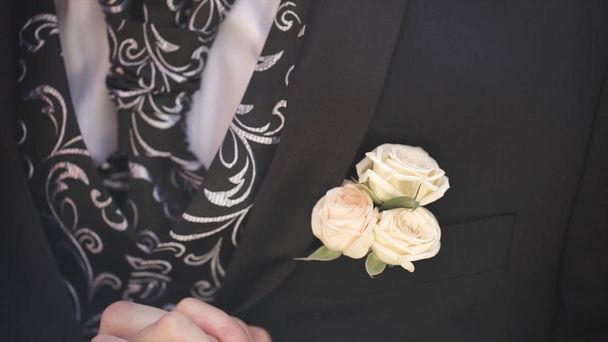 Nelkenblüte in der Tasche. die Blume in der Jackentasche. Anstecknadel mit dekorativen weißen Blumen, die an die Jacke des Bräutigams geheftet sind. boutonniere Blume in der Tasche des Bräutigams bei der Trauung - Foto, Bild