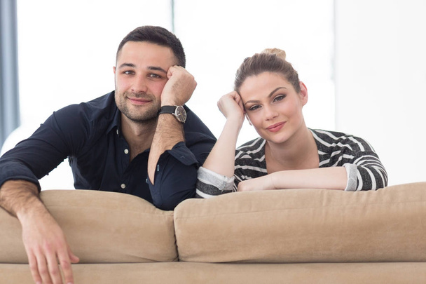 Portrait of young couple sitting on sofa - Foto, afbeelding