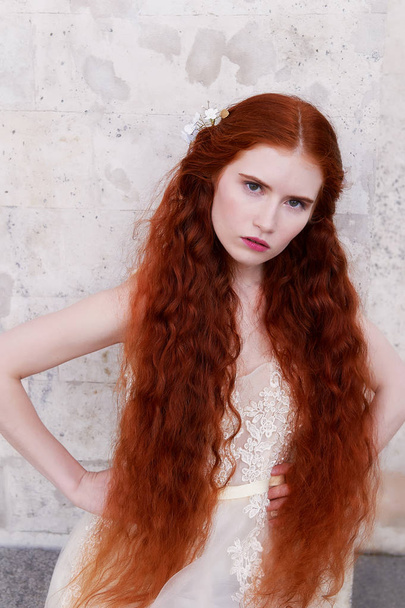 Beautiful red-haired girl with long curly hair in the bride, in a long lace dress.A natural beauty. - Φωτογραφία, εικόνα