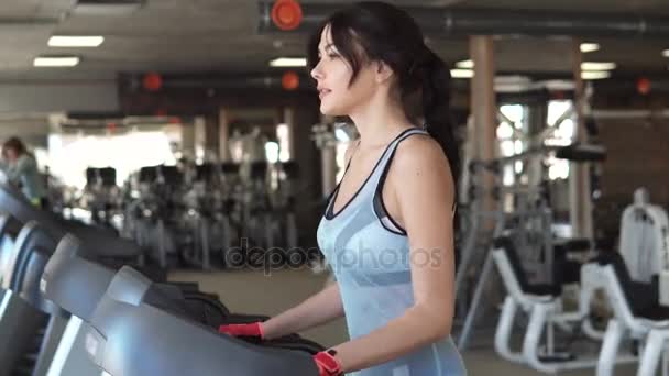 Молодая женщина ходит по беговой дорожке в спортзале. кардио упражнения в тренажерном зале
 - Кадры, видео