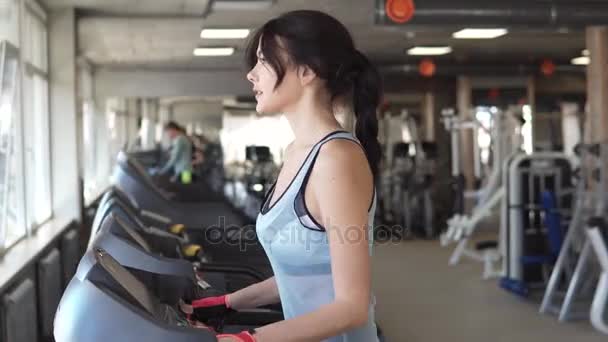 Eine junge Frau läuft im Fitnessstudio auf einem Laufband. Ausdauerübungen im Fitnessstudio - Filmmaterial, Video