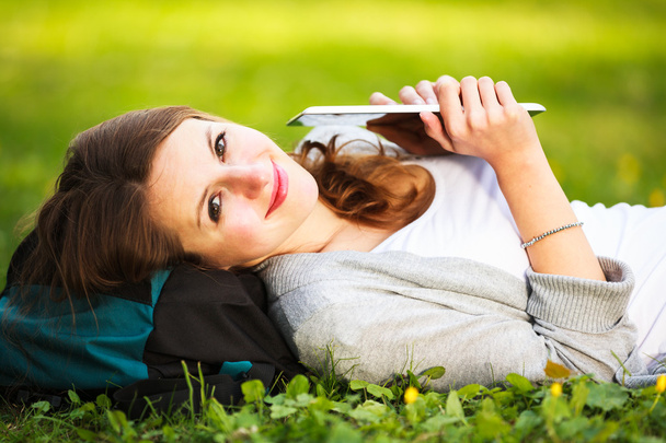 Young woman using her tablet computer while relaxing outdoors in - Fotoğraf, Görsel