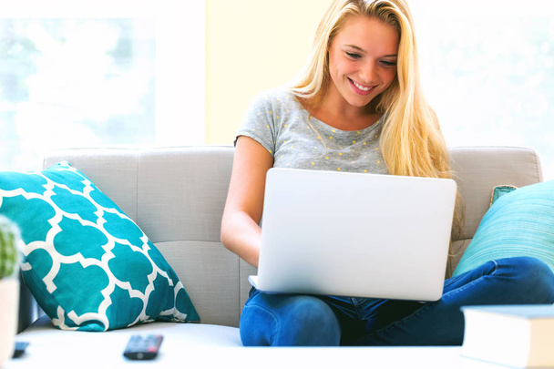 Young woman using her laptop in on her couch - Foto, immagini