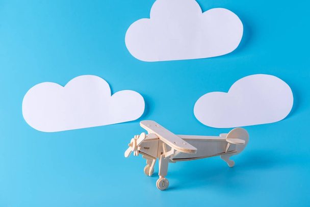 Дерев'яний іграшковий літак на тлі блакитного неба з паперовими хмарами. Концепція подорожей та авіакомпаній
 - Фото, зображення