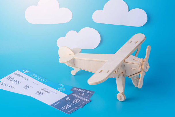 Houten speelgoed vliegtuig en tickets op een achtergrond van blauwe hemel met wolken van papier. Concept reizen en de luchtvaartmaatschappijen - Foto, afbeelding