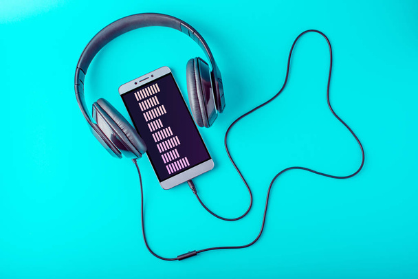Ekolayzır ile mavi bir arka plan üzerinde müzik kulaklık telefon ekranında - Fotoğraf, Görsel