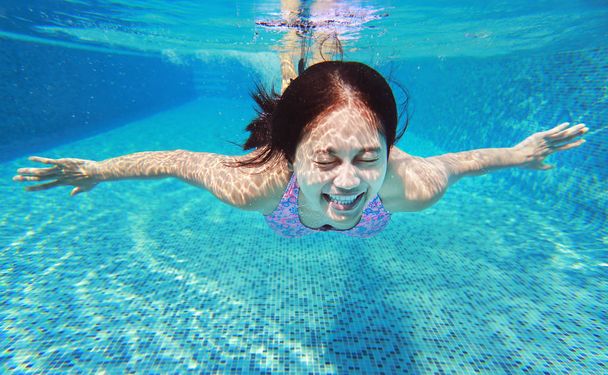 Underwater shot of young woman diving into the swimming pool. - Foto, immagini