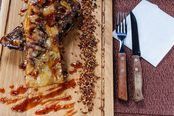 Grilované vepřové maso steak na dřevěné krájecí desky nad dřevěný stůl. - Fotografie, Obrázek