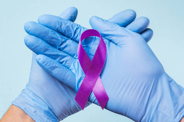 Purple plum ribbon on helping hand support for raising awareness - 写真・画像