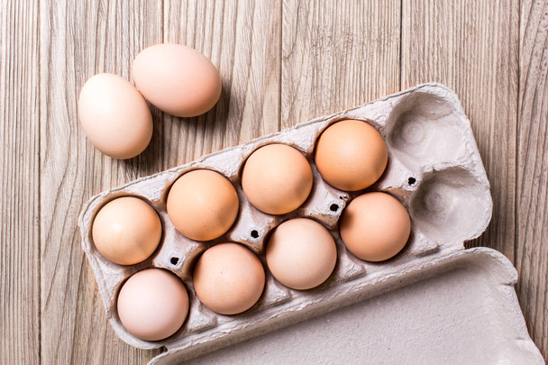 Курячі яйця в картонній коробці на тлі табуретки
 - Фото, зображення