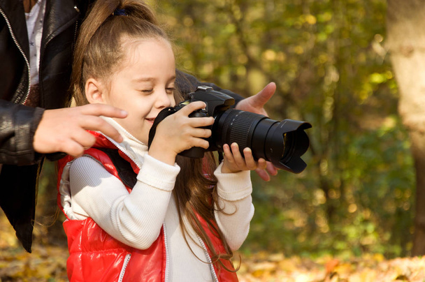 little girl is holding a camera and taking a photo. hobby. - Foto, Bild